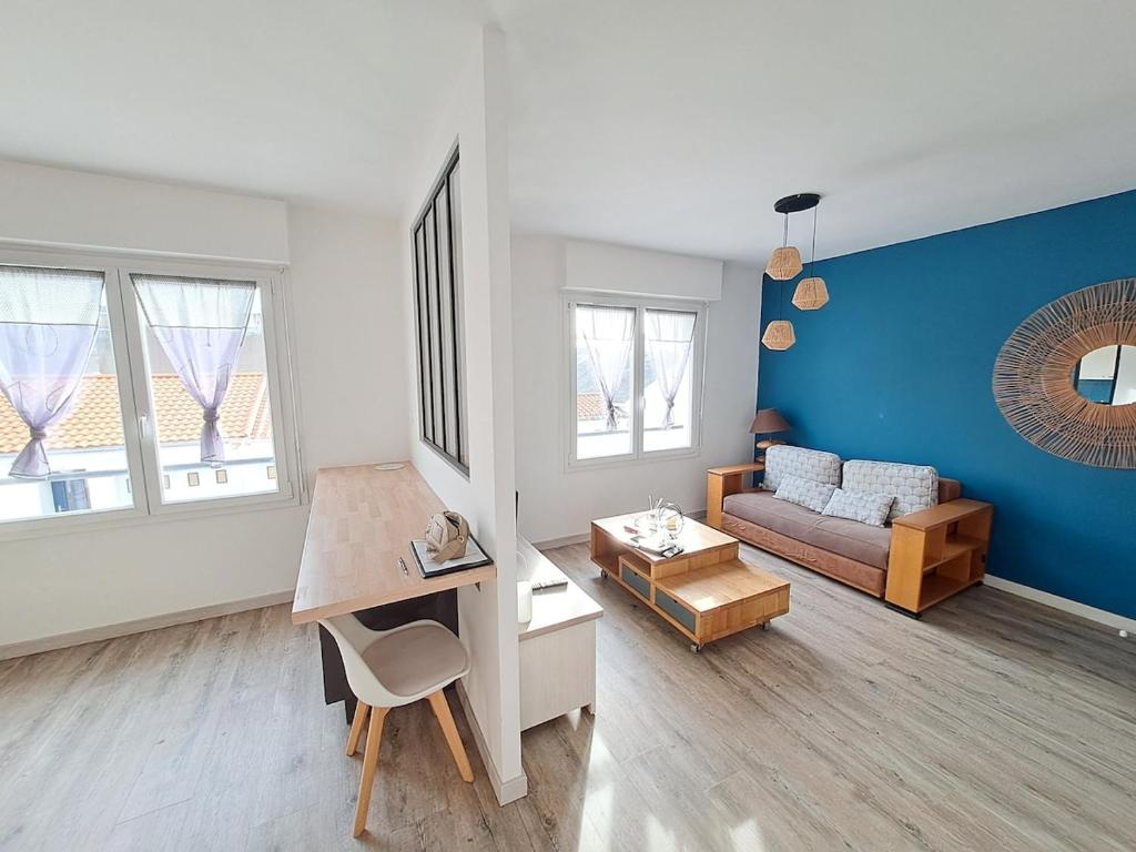 un salon avec un canapé et un mur bleu dans l'établissement L'appart en hyper centre, à Challans