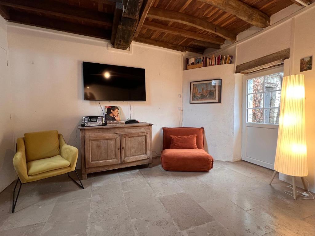 a living room with two chairs and a flat screen tv at La Petite Ecluse in Tanlay