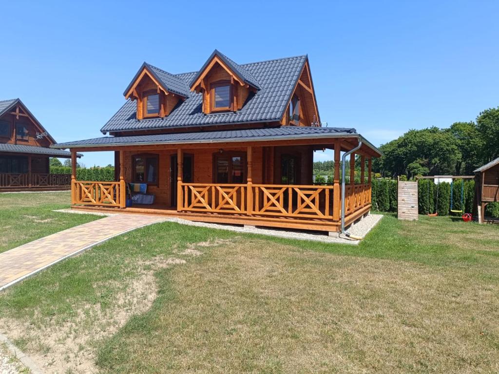 a large wooden house with a large deck at Domki z klimatyzacją in Prażmowo