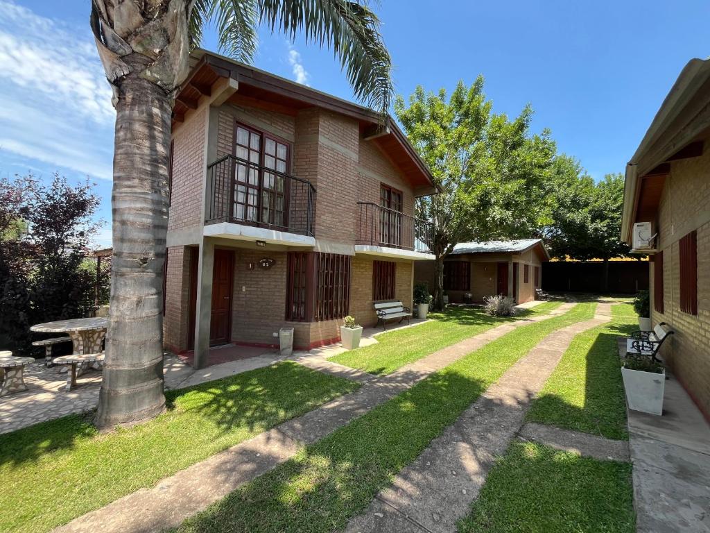 ein Haus mit einer Palme im Hof in der Unterkunft Cabañas Los Aromos in Embalse
