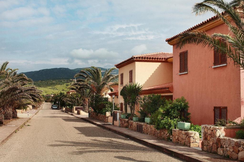 eine Straße mit Palmen und einem rosa Gebäude in der Unterkunft Verande Tanca Torre in Isola Rossa