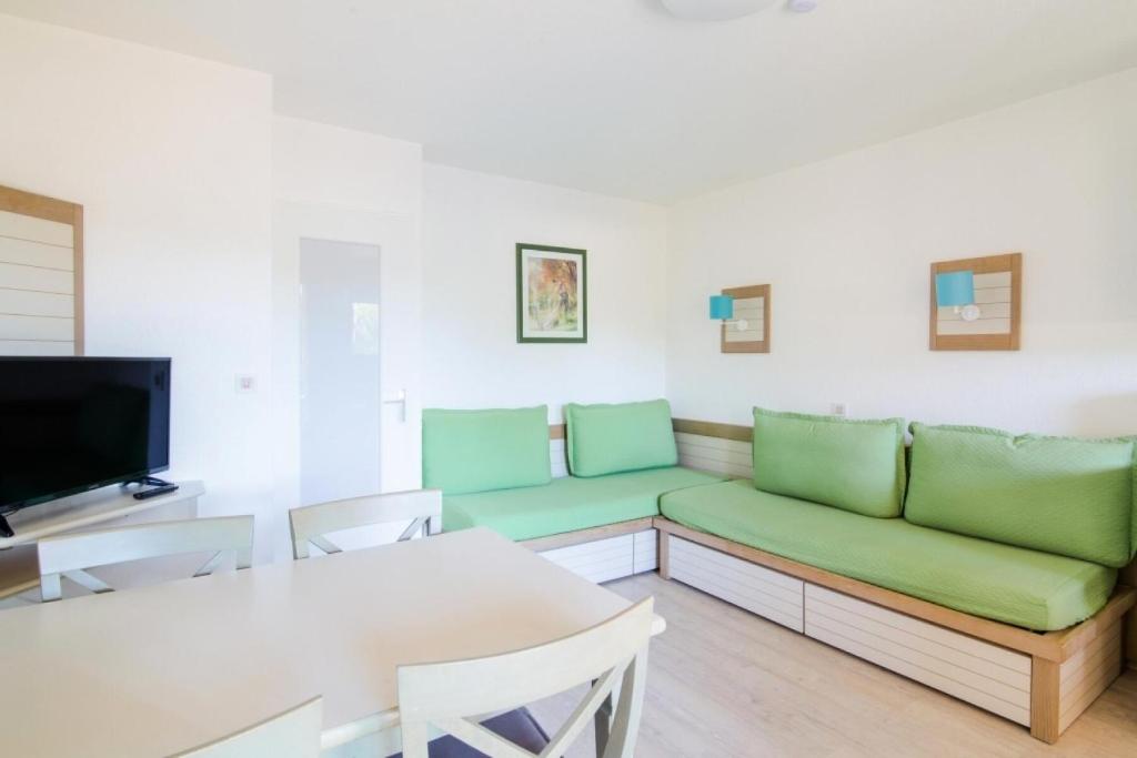 un salon avec un canapé vert et une table dans l'établissement Résidence Saint-Raphaël Valescure - maeva Home - Studio 4 Personnes - Sélection MAE-4651, à Valescure