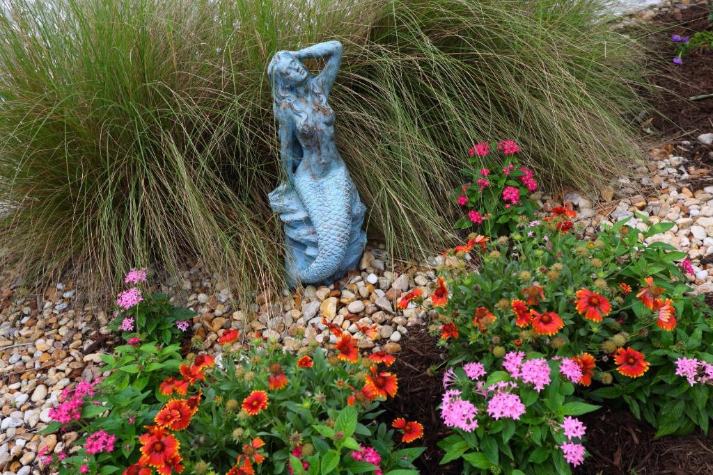 a statue of a woman in a garden with flowers at Marco Island Lakeside Inn in Marco Island