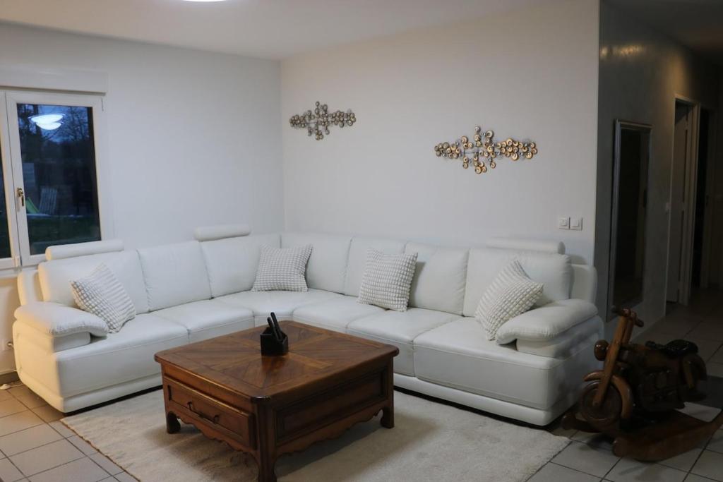a living room with a white couch and a coffee table at L'Orée du Bois in Longeville-lès-Saint-Avold