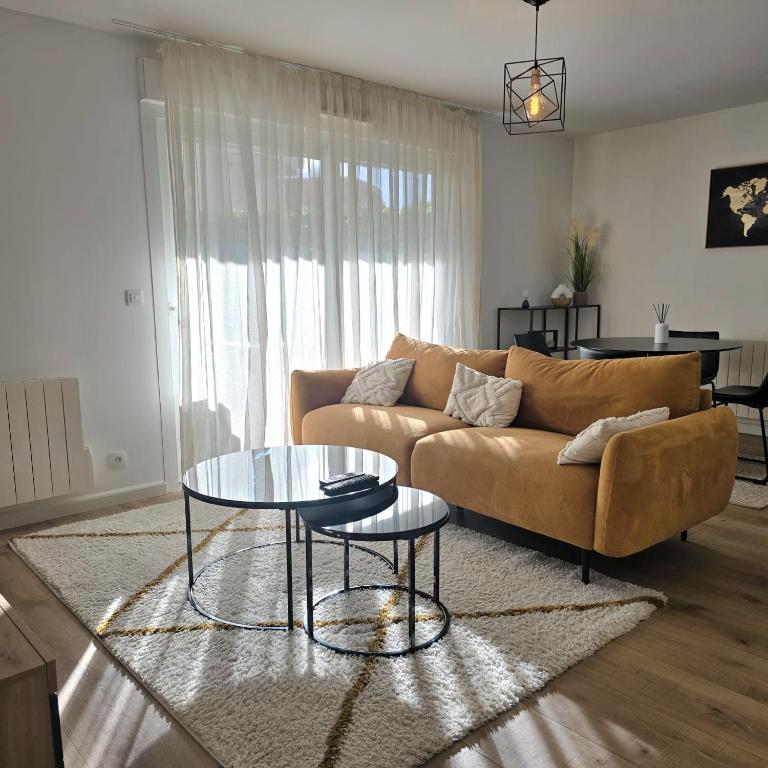 un salon avec un canapé et une table en verre dans l'établissement L'Apaisant, à Thonon-les-Bains