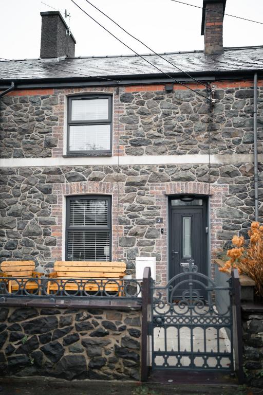 a stone house with a bench in front of it at Snowdonia Quarryman cottage in Llanberis