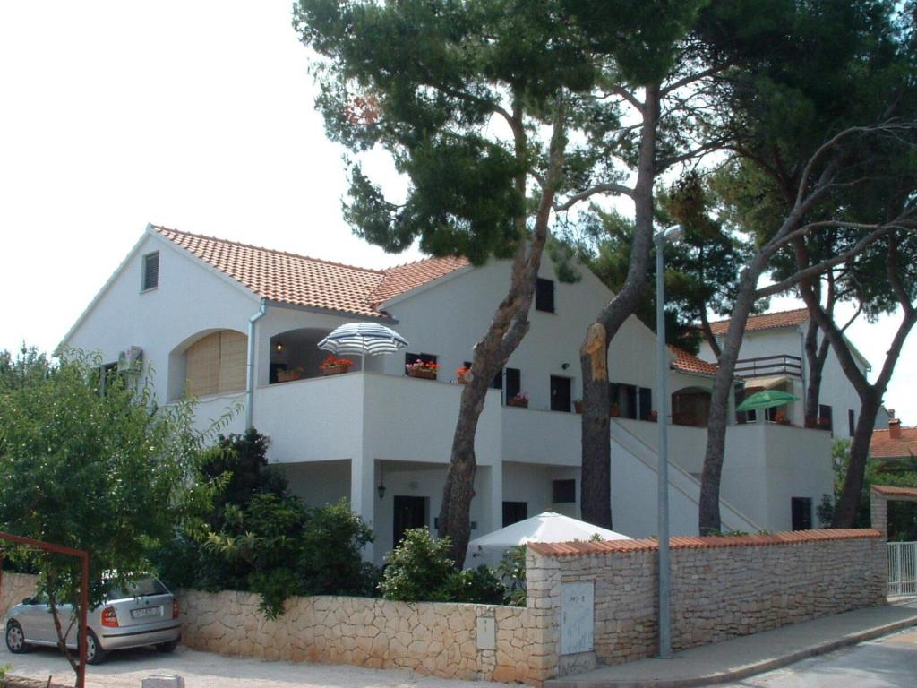 a white house with trees in front of it at Apartments Dinka in Mirce