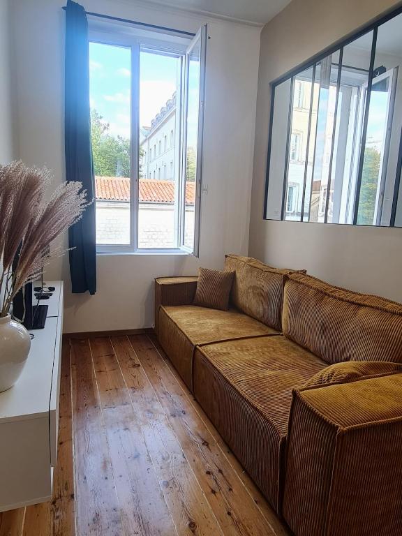 - un salon avec un canapé brun et 2 fenêtres dans l'établissement Jérémy, à Rochefort