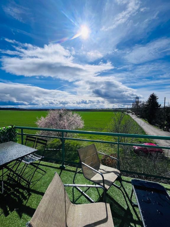 d'un balcon avec des chaises et une table offrant une vue sur un champ. dans l'établissement Le belle vue à Horbourg-Whir, à Horbourg-Wihr