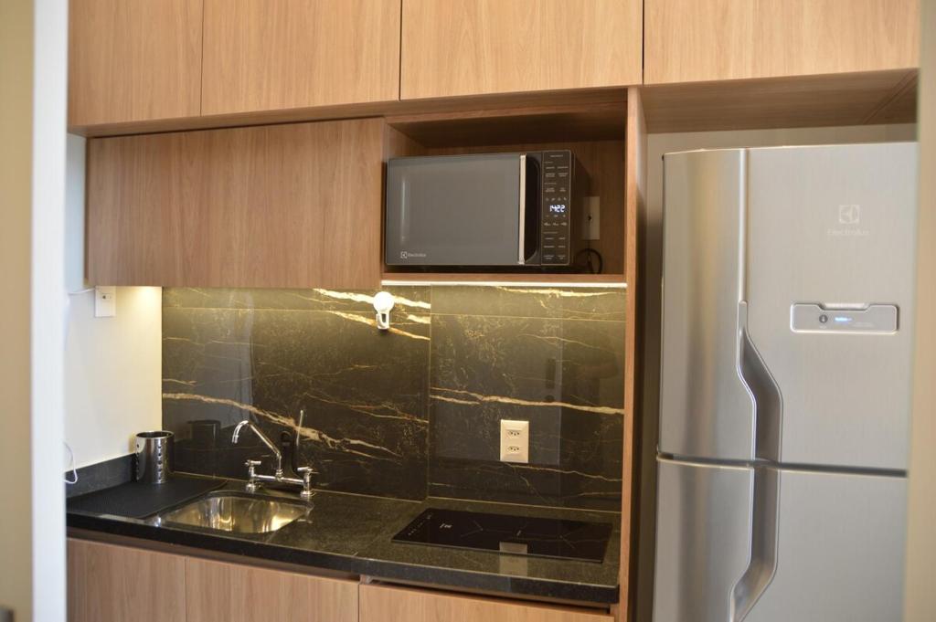 uma cozinha com um frigorífico de aço inoxidável e um micro-ondas em Studio 500m from Allianz Parque em São Paulo