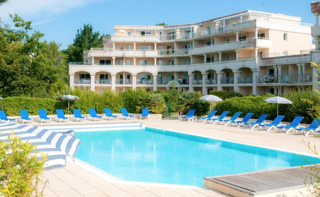 une piscine avec des chaises et un hôtel en arrière-plan dans l'établissement Appartement proche mer dans résidence avec piscine, à La Baule