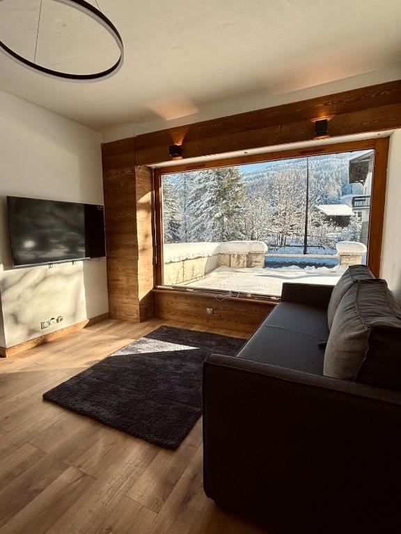 un salon avec un canapé et une grande fenêtre dans l'établissement Charmant appartement aux portes de Megeve, à Demi-Quartier