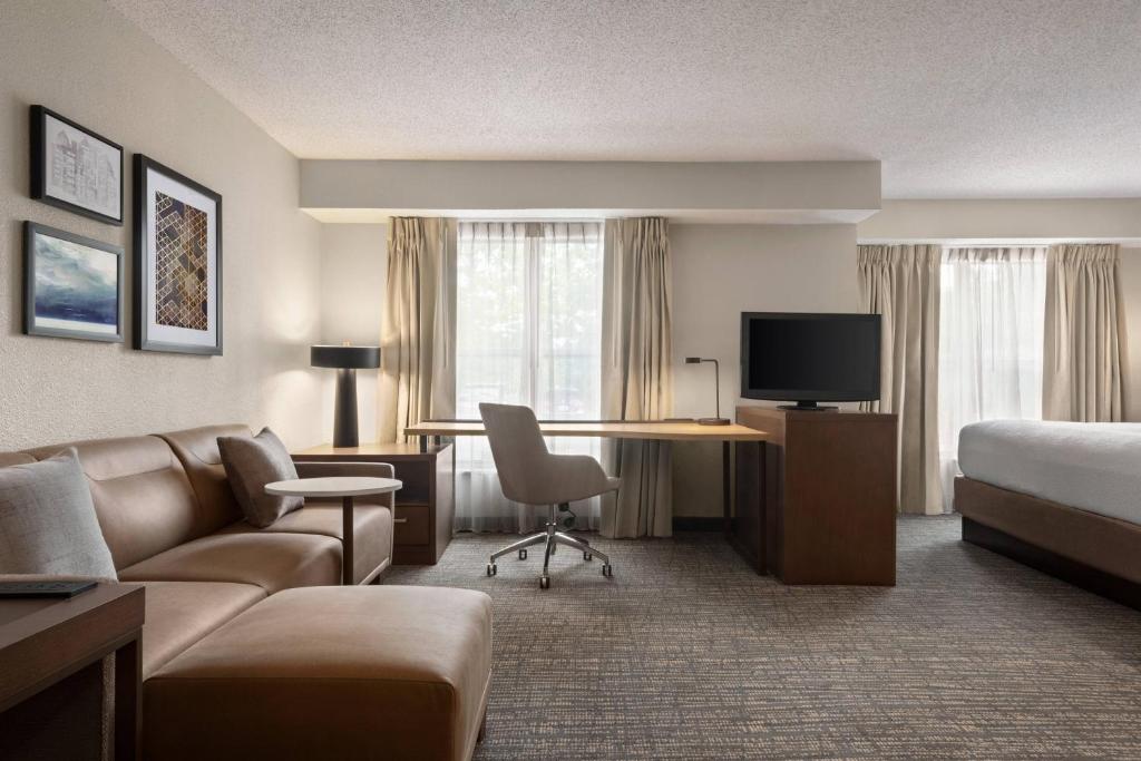 インデペンデンスにあるResidence Inn Kansas City Independenceのベッド、ソファ、デスクが備わるホテルルームです。