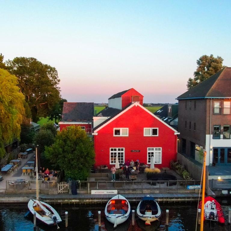 a red building with boats docked in a harbor at Schippershuis in Elahuizen