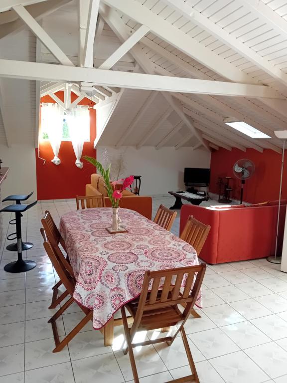 a dining room with a table with a vase of flowers on it at Haut de Villa LA FLEUR DE CANNE in Lamentin