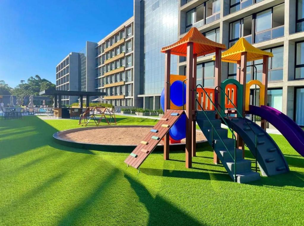 a playground in front of a building with a slide at Charmoso Loft em Resort in Xangri-lá