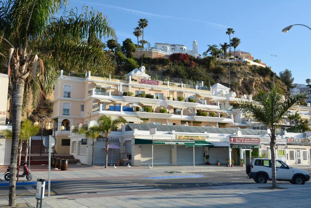 
a beach with a beach house and a building at Apartamentos HC Burriana Playa in Nerja
