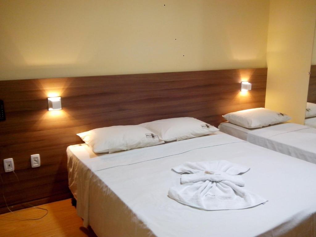 a bedroom with two beds with white sheets at Estação Hotel in Castanhal