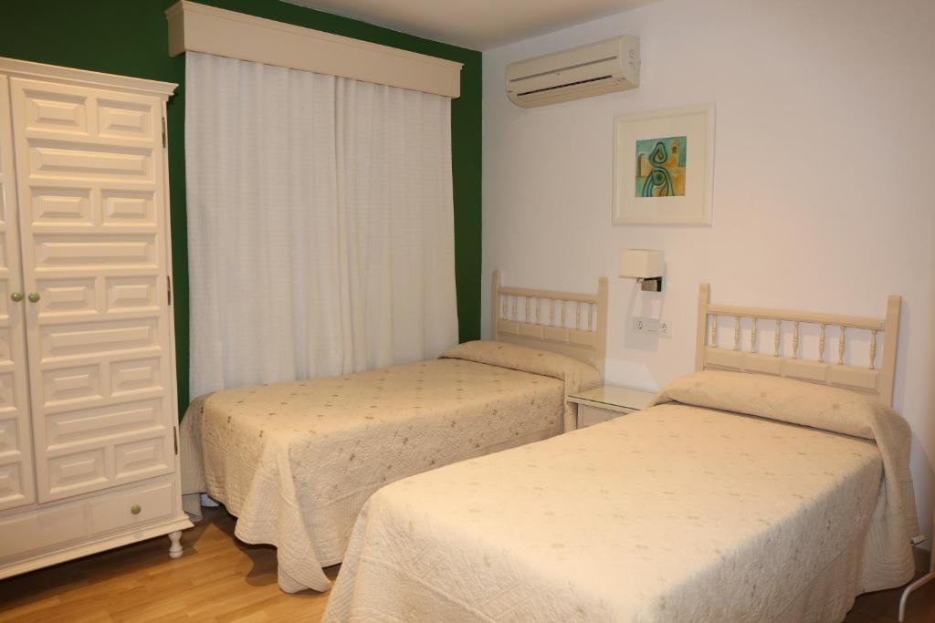 2 camas en una habitación con paredes verdes en Hostal La Janda en Vejer de la Frontera