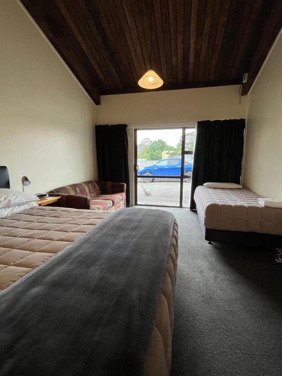 a bedroom with two beds and a sliding glass door at Alpine Motel in Ohakune