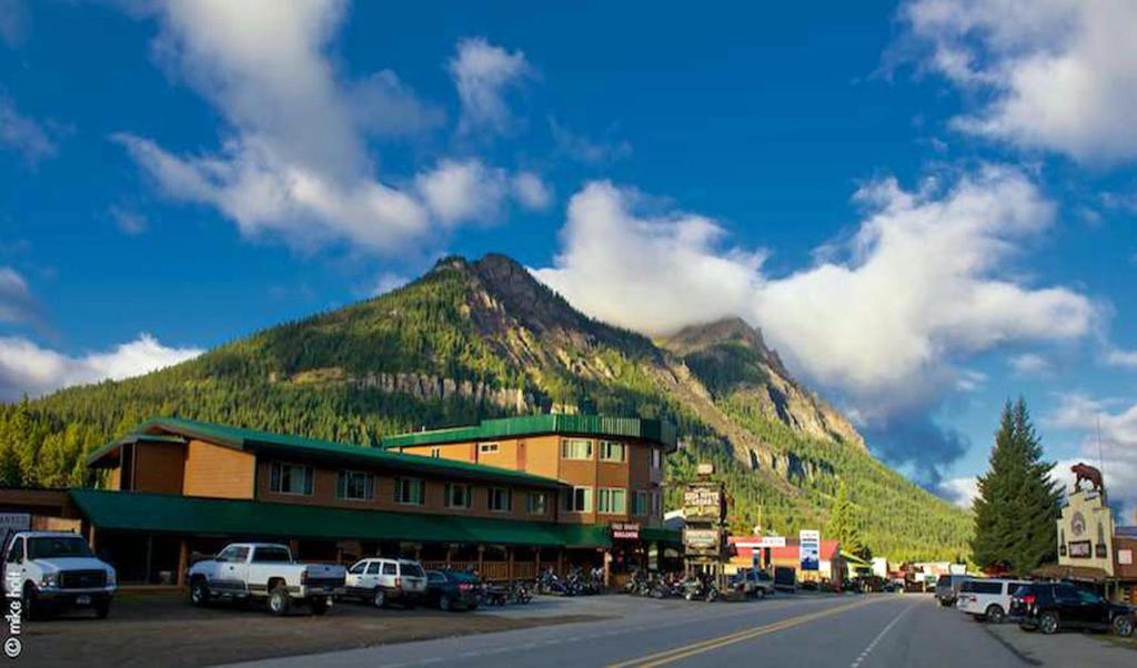 a mountain in the background of a town with a building at Soda Butte Lodge in Cooke City