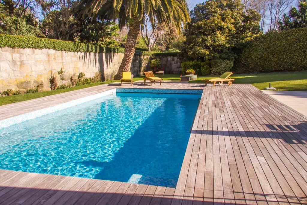 a swimming pool in a yard with a wooden deck at Liiiving in Porto | Oporto Garden Pool House in Porto