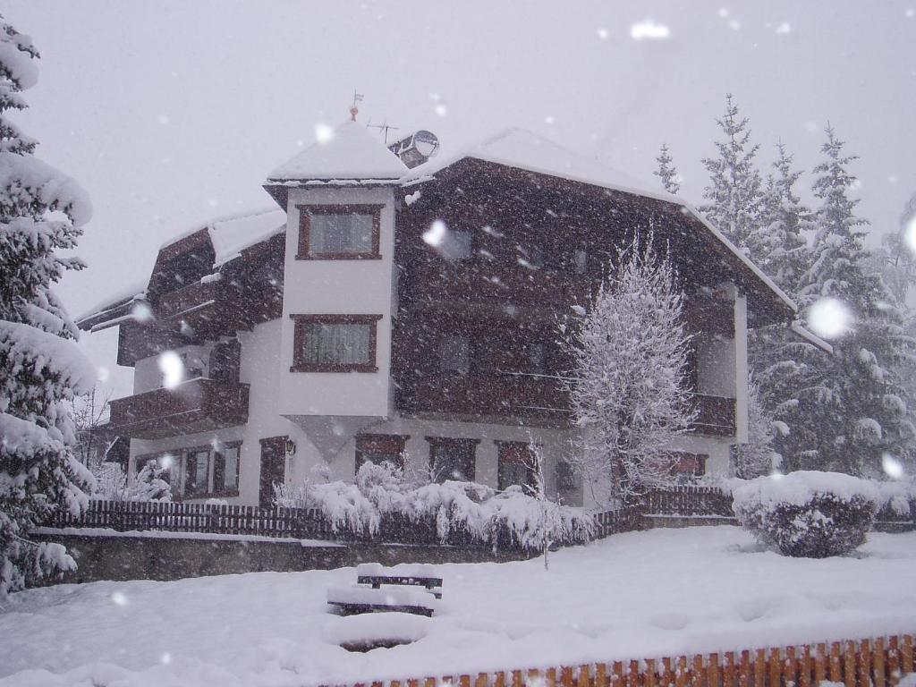 a house covered in snow in a yard at Garni Sayonara in San Vigilio Di Marebbe