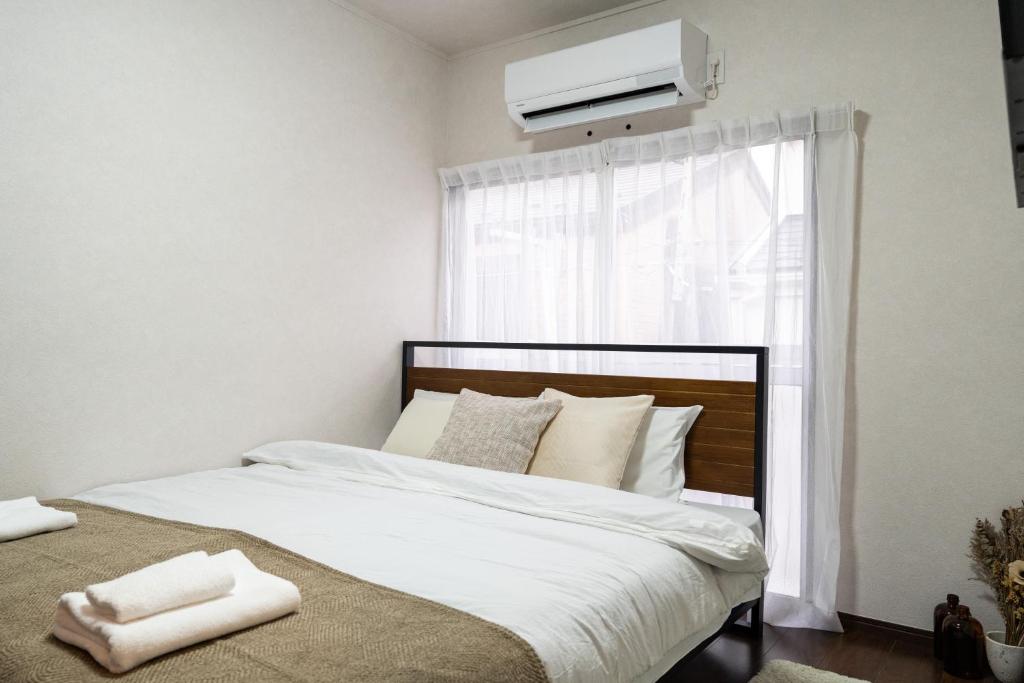 a bedroom with a white bed and a window at ohayo旅館 東矢口 in Tokyo