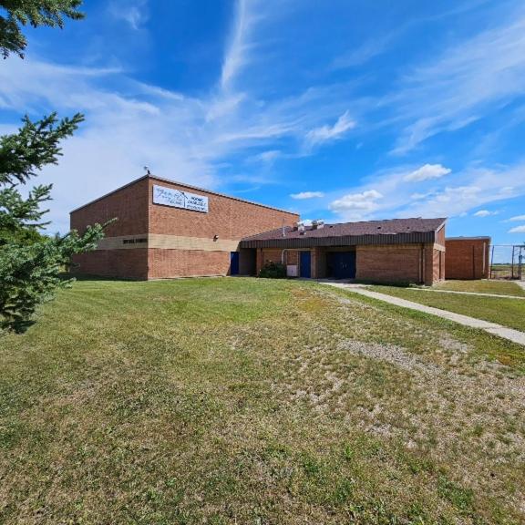 ein großes Backsteingebäude mit einem Grasfeld davor in der Unterkunft Under Living Skies Housing Ltd in Spy Hill