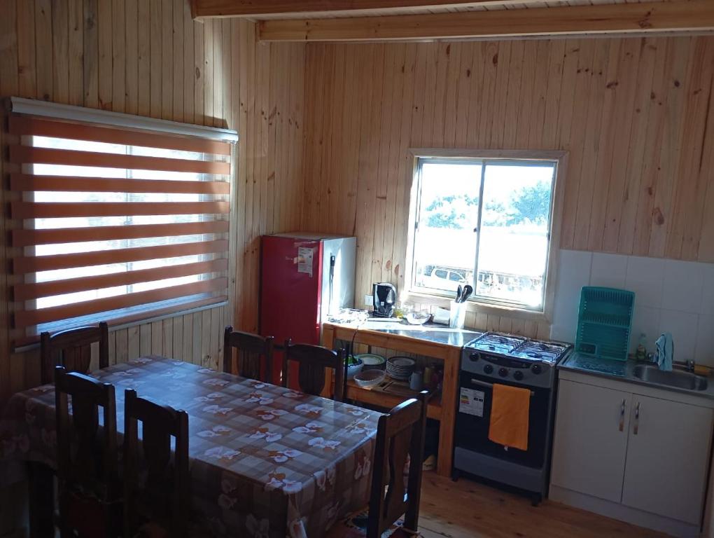 a kitchen with a table and a refrigerator and a stove at Cabaña el descanso in Pelluhue