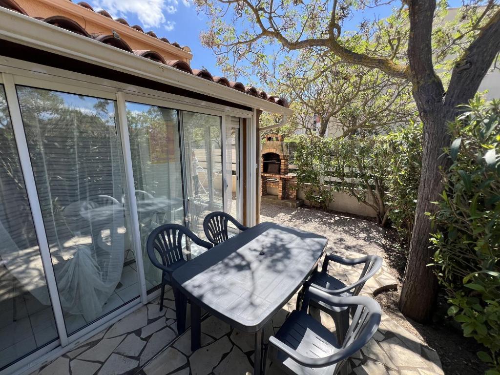 une table et des chaises assises sur une terrasse dans l'établissement Pavillon 6 pers, piscine, clim, parking, proche mer - FR-1-781-77, à Valras-Plage