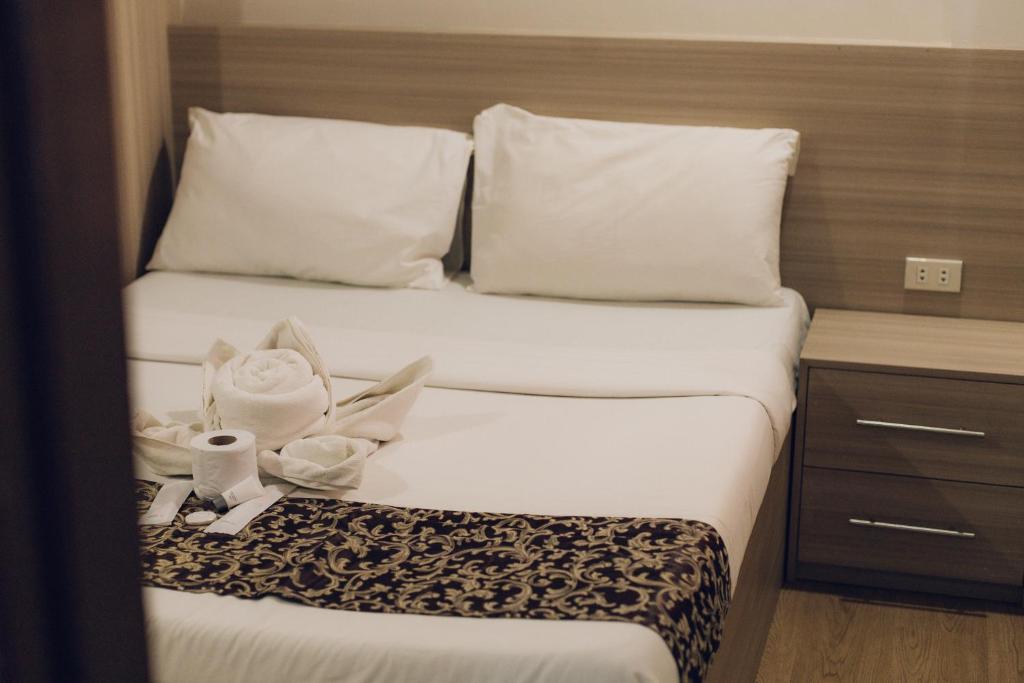 a hotel room with a bed with white sheets and pillows at Elyseah Condotel, Angeles Pampanga in Angeles