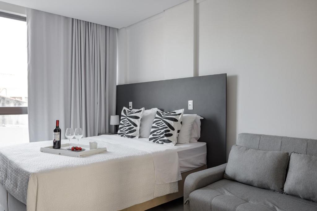 a white bedroom with a bed and a couch at Feel Home - Flat Romântico com Piscina no Rooftop in Cabedelo