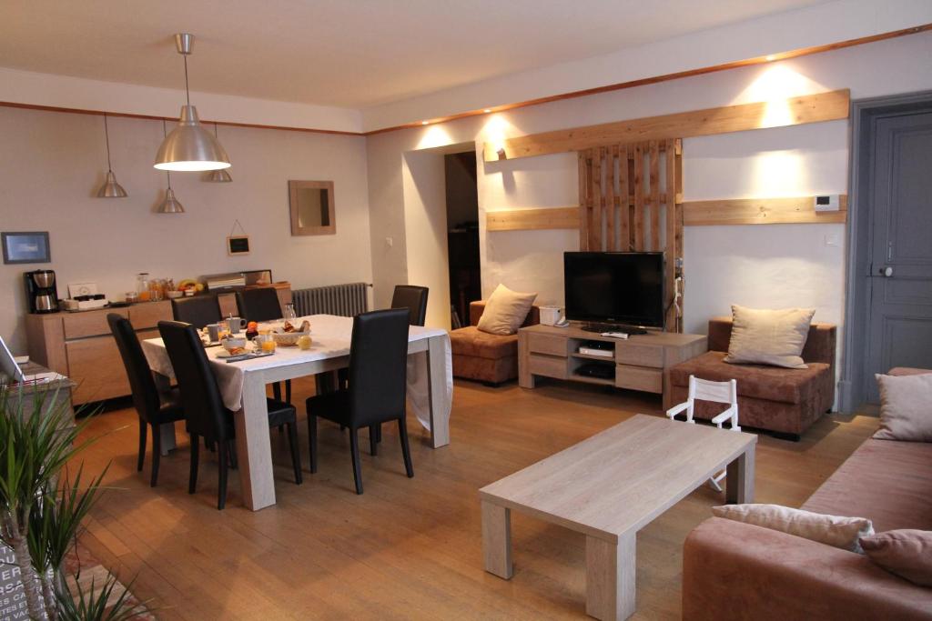 un salon avec une table à manger et un salon dans l'établissement La Grange des Griottiers, à Saint-Priest