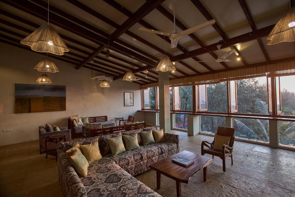 a living room with a couch and tables and windows at Artist Beach House in Morjim