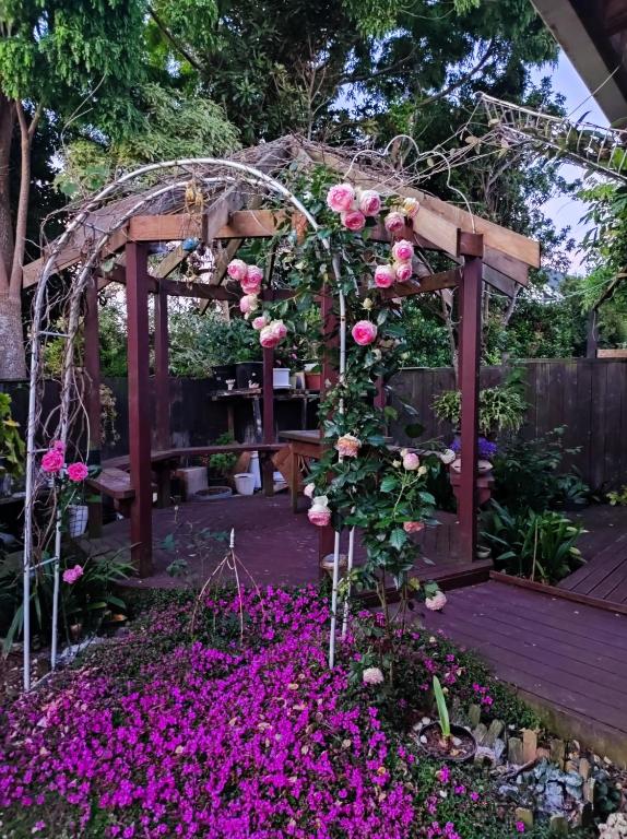 a garden with a pergola and pink flowers at Love House in Auckland
