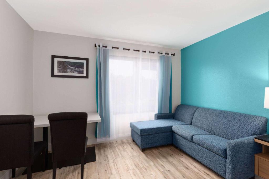 a living room with a blue couch and a desk at La Quinta by Wyndham Sevierville / Kodak in Sevierville