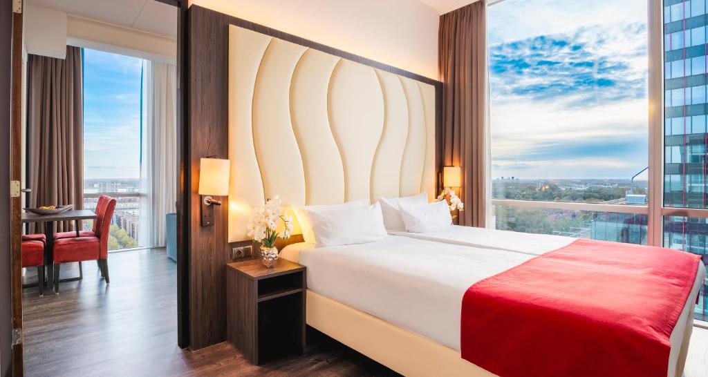 a bedroom with a large bed and a large window at PLAZA Premium Almere in Almere