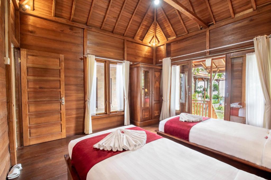 Duas camas num quarto com paredes e janelas de madeira em Swan Beach Inn em Nusa Penida
