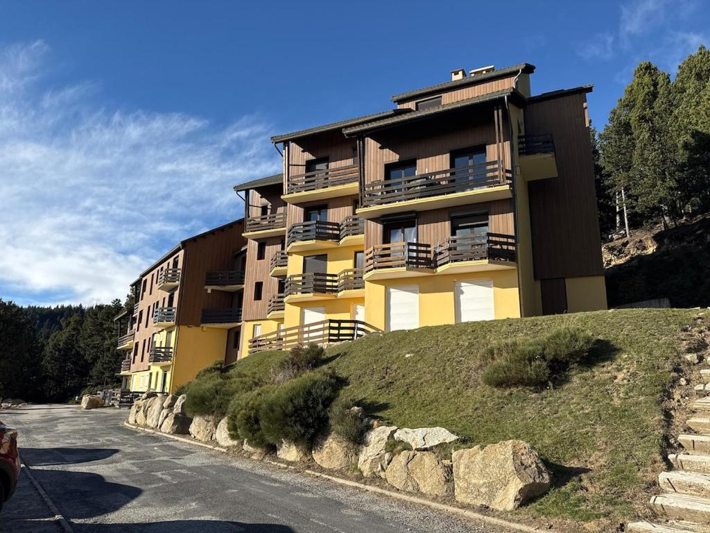 un grand bâtiment jaune au sommet d'une colline dans l'établissement Studio pied des pistes Pyrenees 2000, à Bolquère-Pyrénées 2000