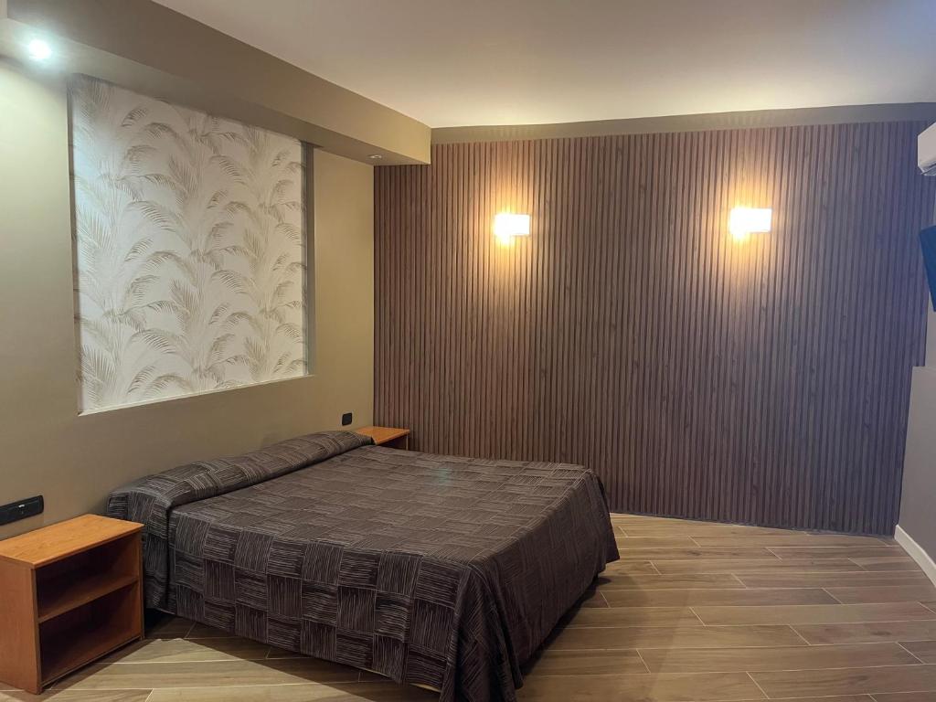 una camera con un letto e due luci sul muro di Hotel Ginepro a Qualiano
