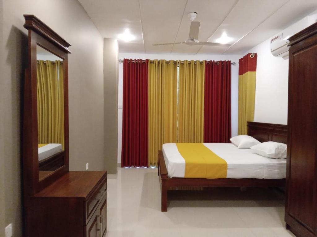 a bedroom with a bed and a mirror and curtains at Dil Apartments 2 in Mount Lavinia
