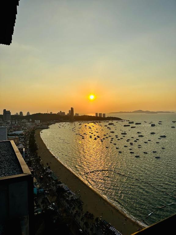 a sunset over a beach with boats in the water at Pattaya Condo Wongamat Privacy Resort - Naklua in North Pattaya