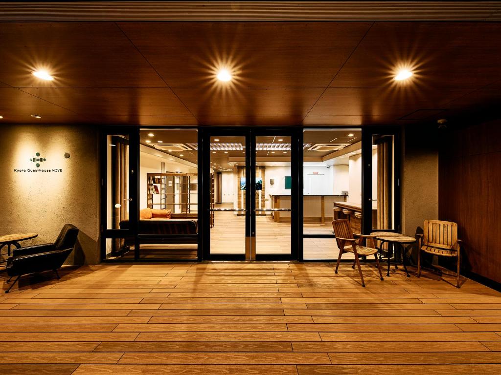 a lobby with glass doors and tables and chairs at Kyoto Guesthouse HIVE in Kyoto