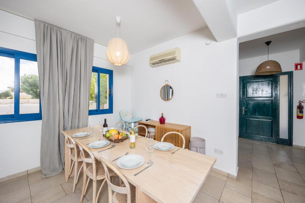 a dining room with a wooden table and chairs at Azzurro Holiday Villas in Peyia