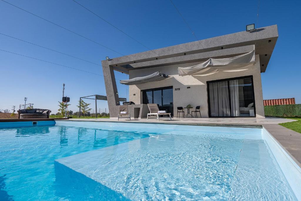 a villa with a swimming pool in front of a house at נופש Eylim-מתחם אירוח מהמם עם 3 סוויטות ובריכה מחוממת ומקורה in Sede Ẕevi