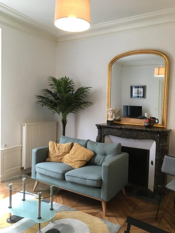 un salon avec un canapé bleu et un miroir dans l'établissement Charmant appartement ancien, lit 160, au Mans