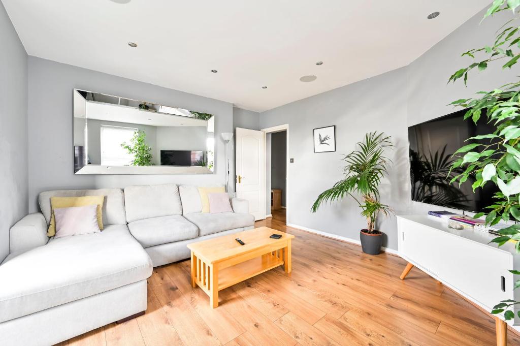 Hotel Cosy 1-Bed E15, sleeps 4, 1 min from tube Station Near O2 Arena, a living room with a white couch and a tv at Cosy 1-Bed E15, sleeps 4, 1 min from tube Station Near O2 Arena in London