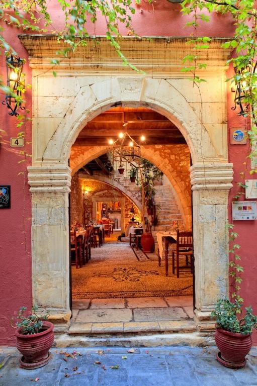 Un arco en un edificio con mesas y sillas. en Veneto Boutique Hotel, en Rethymno
