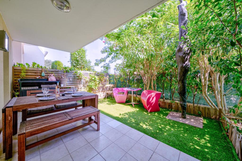 d'une terrasse avec une table en bois et un jardin. dans l'établissement Rez de jardin à 500 m de la plage, à Cagnes-sur-Mer